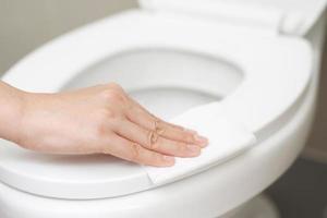woman using tissue paper clean the toilet in the bathroom at home. photo