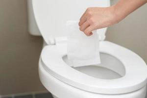 close up hand holding a tissue to be thrown into the toilet bowl. Can not drain water of toilet paper in the toilet bowl cause the stool to clog up. photo