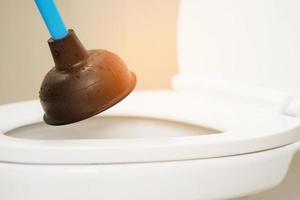 Serviceman repairing toilet with hand plunger. Clogged toilet. photo