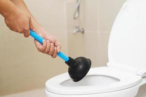 Serviceman repairing toilet with hand plunger. Clogged toilet. photo