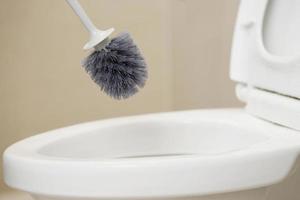 amas de casa utilizar un cepillo a limpiar el baño a eliminar suciedad y tomar cuidado de sanitario mercancía. foto