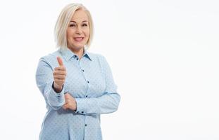 Cheerful smiling blonde business woman lady in blue shirt standing showing Ok gesture looking camera isolated on white background. Selective focus. photo