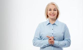 Middle aged businesswoman with folded arms on grey background