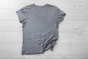 Shirt mockup - pleated, wrinkled t-shirt on white wooden desk top view photo