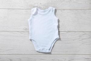 White baby onesie isolated over light wood background. Good for insert your design photo