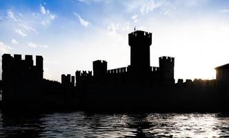 italia - silueta del castillo de sirmone en el lago de garda al atardecer. arquitectura medieval con torre. foto