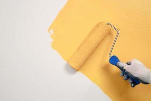 Roller Brush Painting, Worker painting on surface wall  Painting apartment, renovating with yellow color  paint. Leave empty copy space white to write descriptive text beside. photo