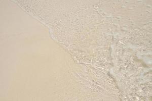 Ocean wave water distribution on sandy white beach photo