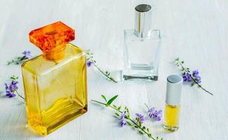 Aromatic Perfume bottles set and flower on the white wooden desk on at wooden background photo