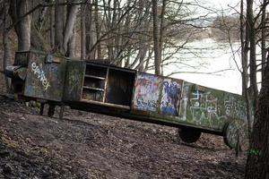 Rusty vintage train carriage abandoned on the hill in the forest near river. Covered in written graffiti drawings metal transport of old times. photo