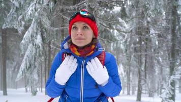 Lonely tourist girl walking on a winter snow-covered coniferous forest in the mountains. Frosty weather. Slow motion video