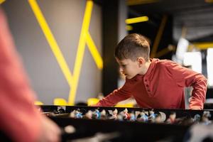 Boy playing table football in kids play center. photo