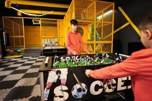 hermanos jugando mesa fútbol americano en niños jugar centro. foto