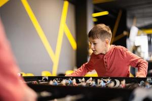 Boy playing table football in kids play center. photo