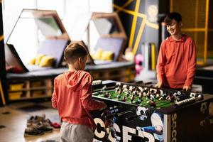 hermanos jugando mesa fútbol americano en niños jugar centro. foto