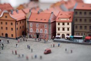 City life with living building facades and people walking at street, aerial view. Urban infrastructure. Model of city street in miniature, tilt shift. Created with photo