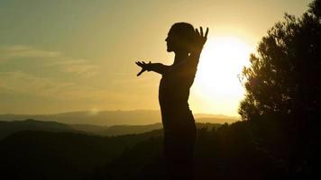 uma fêmea praticando ioga dentro uma lindo natureza configuração em topo do uma montanha às pôr do sol video
