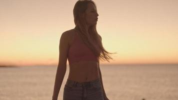 skön kvinna Framställ mot en gnistrande hav och himmel på soluppgång video