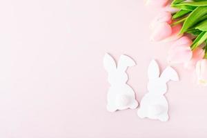 Happy easter couple white rabbits and tulips on pink background top view photo