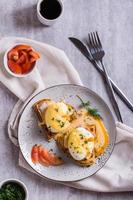 Delicious homemade breakfast with waffles, bacon and eggs benedict on a plate. Top and vertical view photo