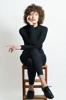 Focused curly haired woman sitting on wooden chair photo