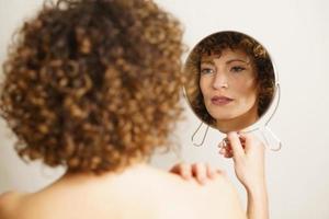 Charming adult female with makeup looking reflection in mirror photo