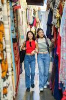 Female tourists shopping clothes in street bazaar photo