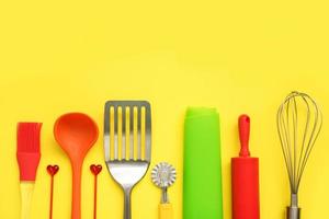 culinary background, culinary accessories on a yellow background - slotted spoon, dough knife, spatula, whisk, brush, skewers, silicone mat, rolling pin, ladle with copy space, culinary background photo