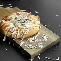 mini pizza topped with grated cheese and some meat photo