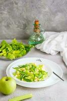 Ready to eat fresh salad of celery, green apple, arugula and sesame seeds on plates on the table. Vegetarian diet. Vertical view photo