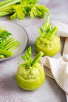 Fresh celery smoothie in glasses and cooking ingredients on the table. Vegetarian diet detox food. Vertical view photo