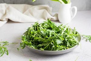 Fresh leaves of arugula on a plate on the table. Organic diet vegetarian food. Lifestyle photo