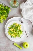 Ready to eat fresh salad of celery, green apple, arugula and sesame seeds on plates on the table. Vegetarian diet. Top and vertical view photo