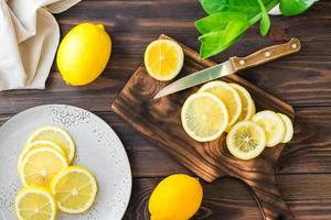 corte maduro limones en un de madera corte tablero y piezas en un plato en el mesa. orgánico nutrición, fuente de vitaminas parte superior ver foto