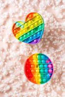 Two silicone rainbow anti-stress toys on the background of fluff. A modern way to relax. Vertical view photo