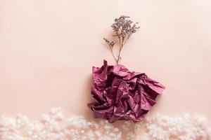The concept of depression and stagnation. Dry flower from a wad of paper on a pink background with fluff. Copy space photo