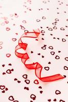 Valentine's Day. Red ribbon in the form of a spiral on a pink background with hearts. Vertical view photo