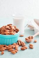 pelado Almendras en un cuenco y almendra Leche en un vaso en un ligero antecedentes. alternativa nutrición, fuente de vitaminas vertical ver foto