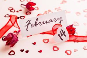 San Valentín día. el fecha de febrero 14 soportes en un rojo cinta y un seco flor en un rosado antecedentes esparcido con corazones