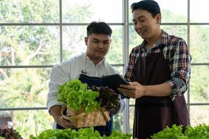 Asian Greengrocer and Worker Using Technology to Organizing Selling Fresh Organic Green Lettuce on Local Market photo