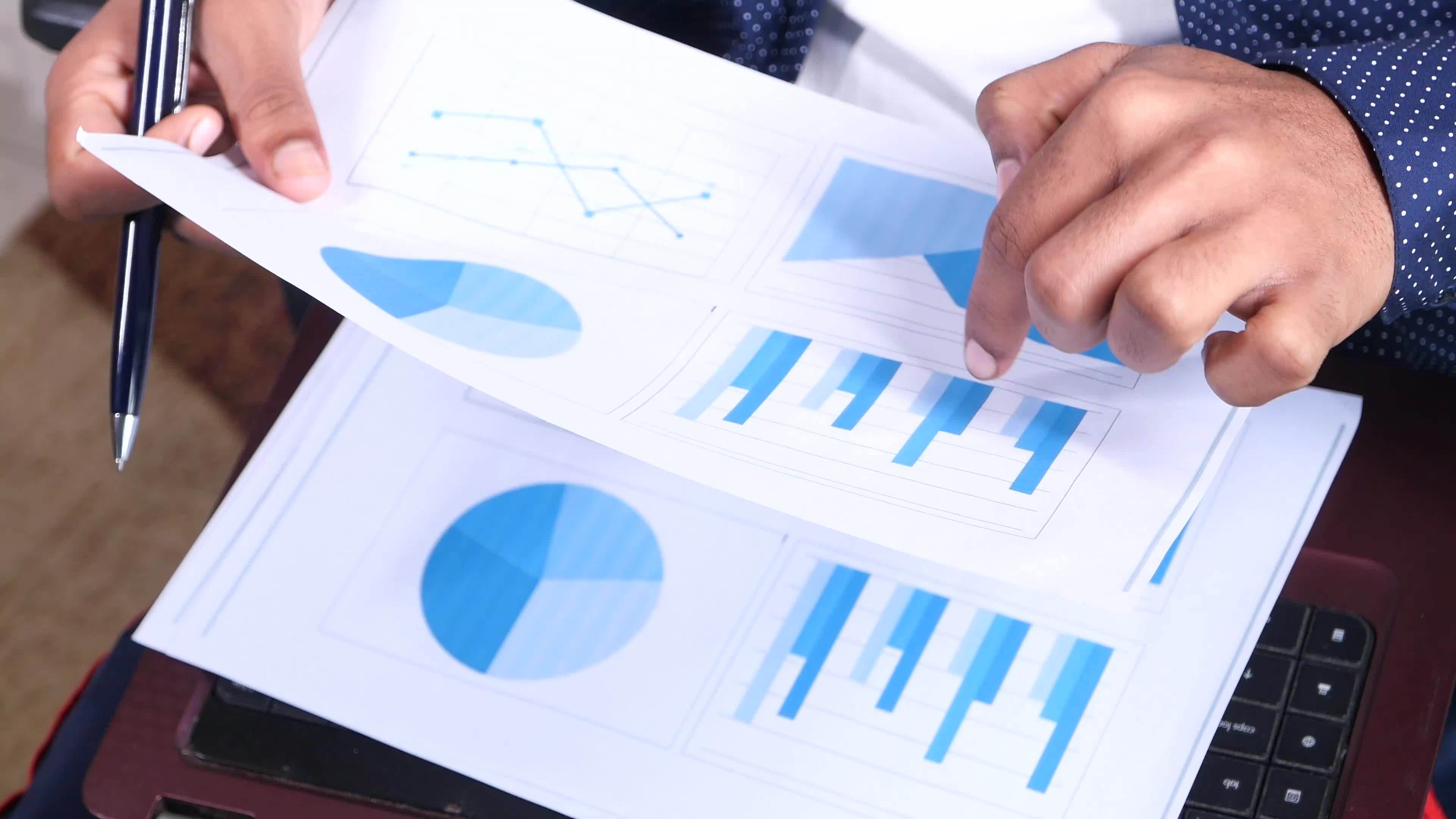 Businessman hand with pen analyzing financial chart on paper 21858771