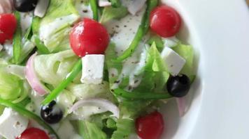 Close up of greek salad in a bowl on table. video