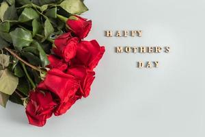 Beautiful bouquet of red roses on a pastel background for Mother's Day. poster. postcard . text in wooden letters of Happy Mother's Day. photo