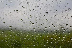 Rain drops on window glasses surface. Rain drops isolated on cloudy background photo