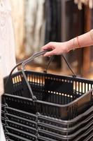 Woman's hand holding an empty basket in the supermarket. Grocery shopping concept. photo