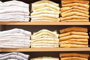 Stack of cotton colorful clothes on table in cloth store. photo