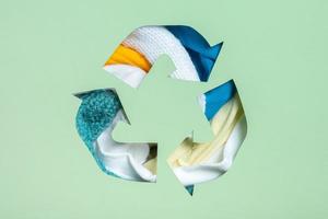 Colorful clothes under paper cut recycling symbol. Second hand, clothing donation and recycling reuse concept photo