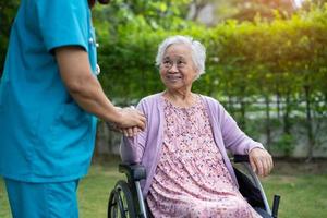 médico ayuda y cuidado asiático mayor mujer paciente sentado en silla de ruedas a parque en enfermería hospital pabellón, sano fuerte médico concepto. foto