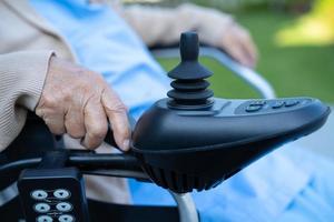 Asian senior woman patient on electric wheelchair with joystick and remote control at hospital. photo