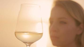 schön Frau halten ein Wein Glas gegen ein funkelnd Meer und Himmel beim Sonnenuntergang video